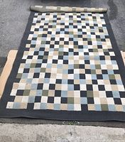 Photo of the carpet fully rolled out showing the checkered pattern and color variations with a black border