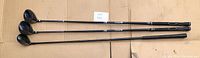 Photo of three golf clubs showing full length, all right-handed, with dark shafts and club heads.