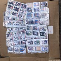 Photo showing an overview of multiple plastic sleeves containing vintage baseball and hockey cards arranged on cardboard.