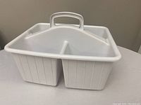 Front side of the white plastic cleaning caddy showing its two large compartments divided in the middle and a handle at the top center.