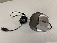 Single ergonomic wired mouse with USB cable, silver and grey color designed for right hand.