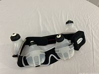 Black FuelBelt exercise belt with three clear water bottles and small pouch laid flat on white surface.