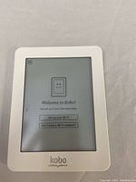 Front view of white Kobo Mini eReader powered on displaying Welcome to Kobo setup screen with Wi-Fi options.