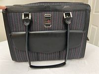 Front view of the black and patterned laptop bag with leather handles and flap pocket.