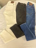 Photo of three pairs of Lucky Brand women’s jeans in white, black, and blue denim laid side by side showing the back pockets and leather brand patches.