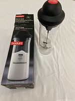 Battery operated milk frother and original box showing Bodum branding and product information