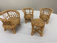 Set of four miniature wicker living room furniture pieces on white surface: loveseat, two chairs, and round table.