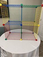 Full view of the six-compartment multi-color wire grid storage cubes on a round table.