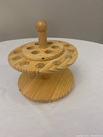 Front view of the wooden spinning organizer showing two circular tiers and a vertical handle in the center. Holes around each tier are visible for holding tools.