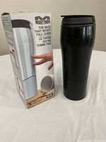 Photo of new MightyMug in box alongside used black MightyMug showing the mug and packaging.