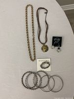 Jewelry items displayed on white surface showing necklaces, earrings, and bangles.