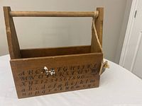 Front side of the wooden basket showing alphabets and numbers stencil in black.