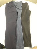 Three pairs of size 2 pants in dark gray, light gray, and olive green laid flat on a surface.