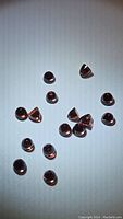 Multiple polished natural Almandine garnet gemstones displaying fancy bullet cut spread on a white background under lighting to show color and shape.