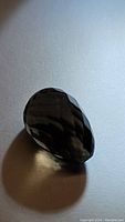 Photo showing the smokey quartz gemstone with faceted briolette cut, highlighting the dark smoky color and clarity.