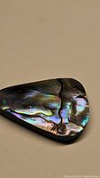 Polished natural abalone doublet gemstone, fancy cut with visible iridescent colors and smooth surface.