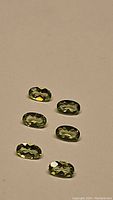 Six oval cut apple green Peridot gemstones arranged with good focus to show size, color and clarity