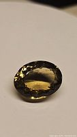 Oval faceted champagne citrine gemstone showing rich golden-brown color and high luster on white background