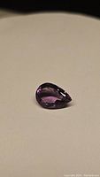 Photo of the 5.42ct natural pear cut purple Brazilian amethyst gemstone showing its facet details and deep purple color.