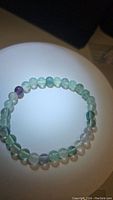 Top view of natural fluorite bead bracelet arranged in a circular shape showing green, purple, and clear beads.