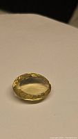 Oval-shaped lemon citrine gemstone with faceted cut on light background, showing light yellow color and transparency.