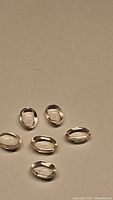 Six natural oval cabochon morganite gemstones on plain background.