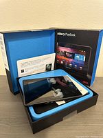 Tablet placed inside original black and blue PlayBook packaging box showing the front of the tablet and box details.