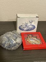 Photo of vintage Dansk collectables boxed candle holder and a small tea set piece wrapped in bubble wrap with its box.