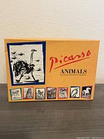 Closed yellow box of Picasso Animals cards with images of various animal sketches on the front.