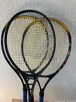 Three vintage tennis rackets grouped overlapping on a wall background.