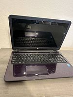 Purple HP laptop open displaying keyboard and screen reflecting background.