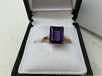 Front view of the ring in a jewelry box showing emerald cut amethyst