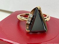 Front view of ring showing triangular amethyst and side clear stones