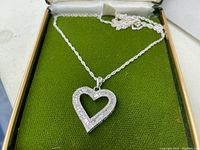 Front view of heart pendant and chain displayed in green-lined jewelry box