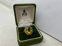 Front view of oval peridot ring in green velvet-lined jewelry box