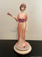 Front view of figurine showing woman in peach dress holding fan