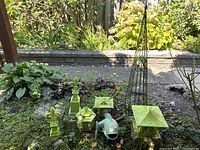 Wide overview of all seven items on ground: obelisk at back, pagoda lanterns, fleur-de-lis finials, koi fish statue