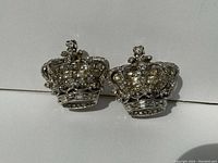 Front view of two crown-shaped rhinestone brooches of duette set