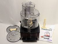 New 14-cup capacity black Cuisinart food processor with two discs, spatula, plunger, and manual laid out on white background.