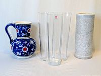 All three vases displayed side by side: blue handpainted ceramic, clear crystal Alvar Aalto, and white marble vase.