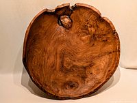 Front view of the large, round burl wood bowl showing grain and a natural knot near the rim.