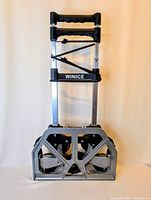 Front view of the folded hand truck showing the WINICE branding, ergonomic handles, and folded base with visible wheels.