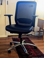 Front-facing photo of the HON office chair showing black mesh back, leather seat, adjustable arms, and chrome base with casters.