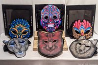 Six LED sound-reactive masks arranged in two rows: three animal face masks on bottom (panther, fox, raccoon) and three abstract pattern masks on top; all unlit on a white surface.
