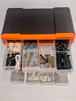 Top front view of a few opened drawers showing screws, dowels, and washers inside.