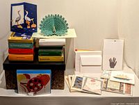 Overview of palm leaf box with stacked colorful boxed greeting cards and loose cards and envelopes arranged around it, displaying diverse designs.