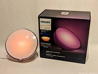 Philips Hue Go lamp illuminated in warm orange light alongside the product box.