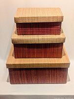Front view of the three stacked nesting storage boxes showing natural lid and reddish woven sides