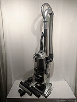 Shark Lift-Away Deluxe vacuum upright with attached hose and five black plastic cleaning attachments arranged in front.