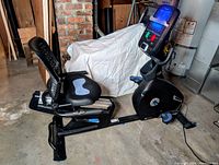 Side view of black Nautilus recumbent exercise bike showing adjustable mesh seat with backrest, pedal assembly, sliding rail and flywheel housing marked R618